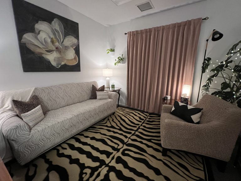 Cozy therapist office with ambient lighting, large couch, and therapist chair.